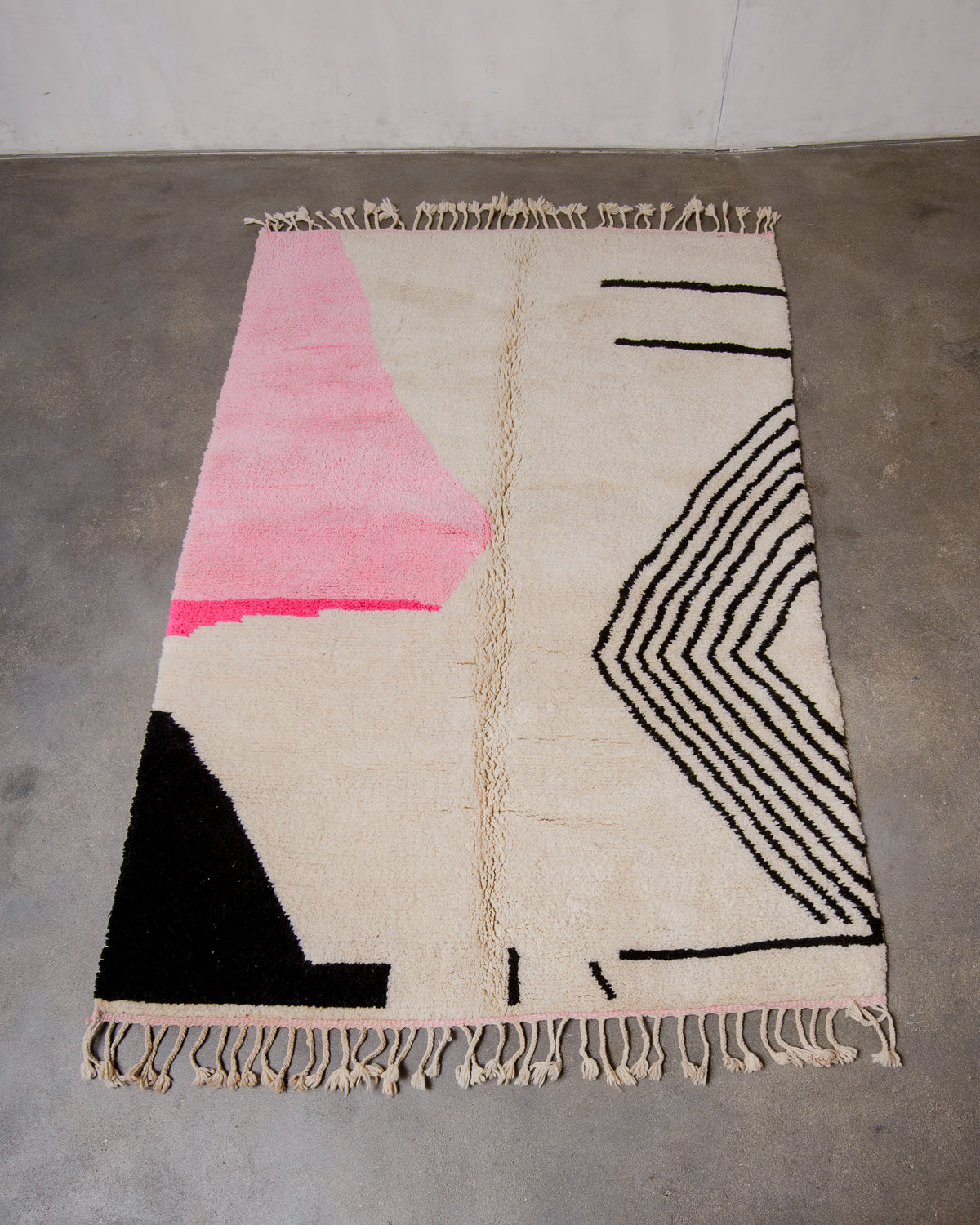 Berberlin Finest Beniourain Rug made of cream wool with a pink and black design laid flat on concrete floor.